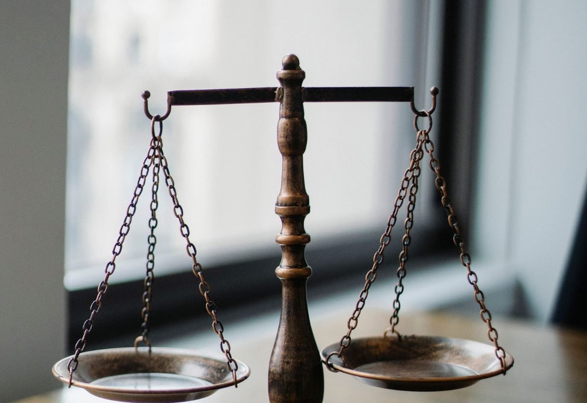 Brass scales of justice and a gavel beside a window