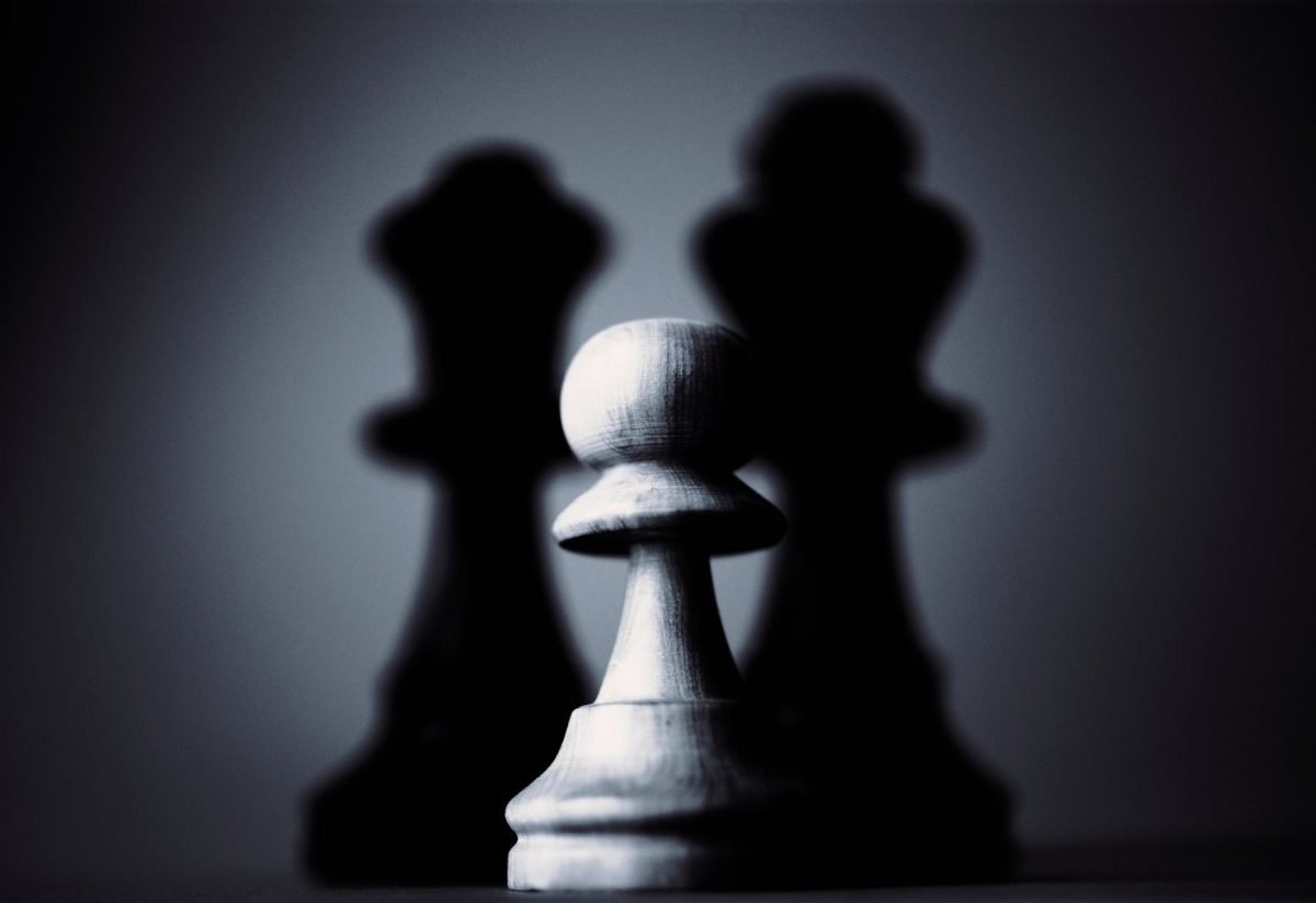 Chess pawn casting a long shadow in black and white